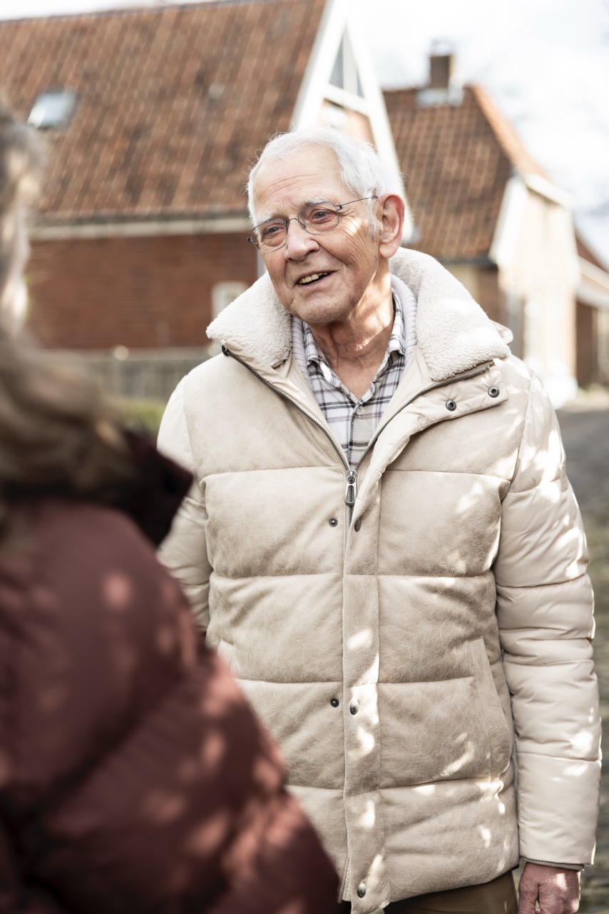 Een man staat in een woonwijk en kijkt een vrouw aan.